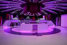 the interior of a building with purple lighting and white counter tops in front of stairs