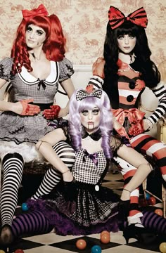 three women dressed in costumes sitting next to each other with candy canes on their feet