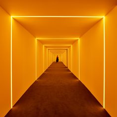 a long hallway with yellow walls and light at the end