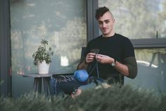 a man sitting on a chair looking at his cell phone while holding a blue ball