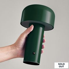 a person holding a green object in their hand with the word sold out on it