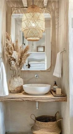 a white sink sitting under a mirror next to a basket filled with dry grass on top of a wooden counter