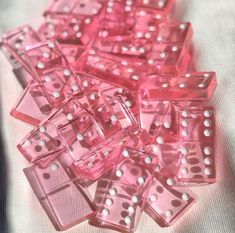 many pink dices are laying on a white tablecloth and some have holes in them