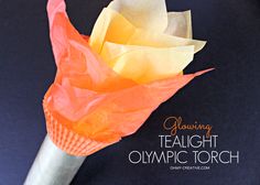 an orange and yellow paper flower on top of a white stick with the words, glowing tealight olympic torch