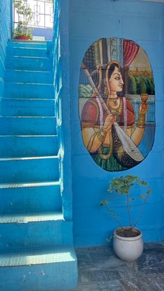 a painting on the side of a building next to a potted plant and stairs