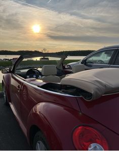 two cars parked next to each other with the sun setting in the distance behind them