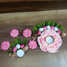 pink and white flowers are arranged on a table next to two small candle holders with candles in them