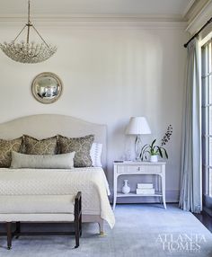 a white bed sitting in a bedroom next to two windows