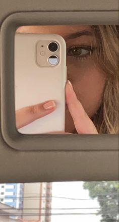 a woman taking a selfie in the mirror with her cell phone up to her face