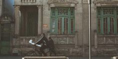 a man riding a bike down a street next to a tall building