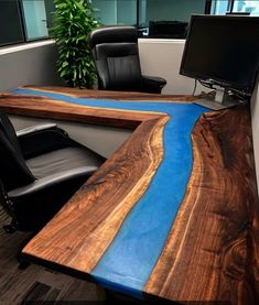 an office desk made out of wood with blue paint on the edge and black leather chairs