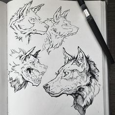 an open book with drawings of wolf heads on it and a pen next to it