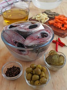 several bowls filled with different types of food on top of a wooden table next to olives and peppers