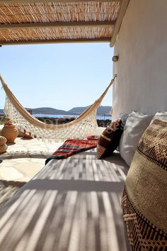 a hammock hanging from the side of a building next to a bed with pillows on it