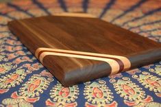 a wooden cutting board sitting on top of a blue and red cloth covered tablecloth