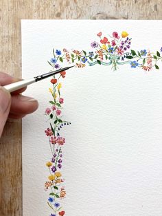 someone is painting flowers on paper with watercolors