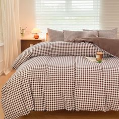 a bed with brown and white checkered sheets in a bedroom next to a window