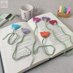 an open book with crocheted flowers on it and some writing utensils