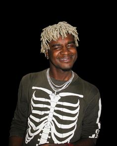 a young man with dreadlocks and a skeleton shirt is smiling for the camera