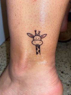 a small giraffe tattoo on the foot of a person's leg,