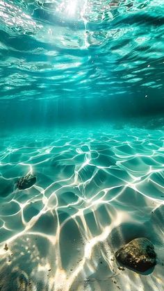 the sun shines through the water as it reflects on the sandy bottom of the ocean floor