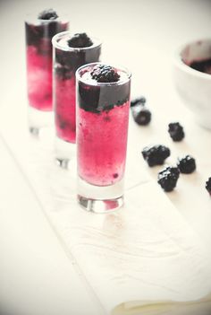 three glasses filled with blueberries and blackberries next to a small bowl of berries