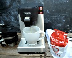 coffee being poured into a cup in front of a grinder and other kitchen items