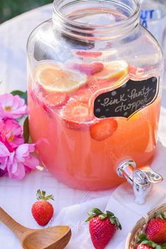 a glass jar filled with pink lemonade and strawberries