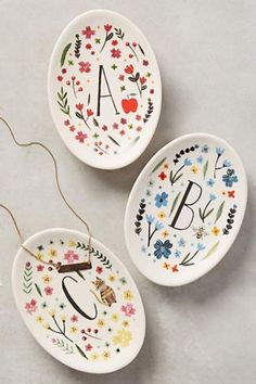 three personalized ceramic dishes with floral designs and the letters a, b, and c