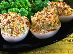 four deviled eggs on a black plate with parsley and seasoning sprinkles