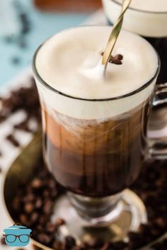 two glasses filled with liquid sitting on top of coffee beans