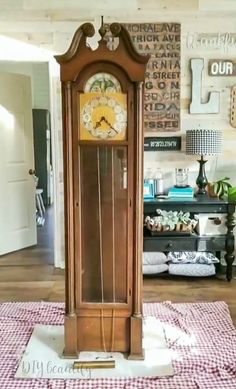 an old grandfather clock sitting on top of a checkered tablecloth in front of a wall