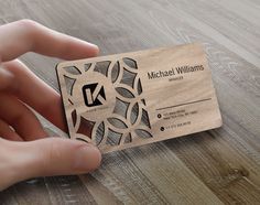 a person holding a business card on top of a wooden table with woodgrain