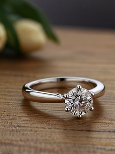 a diamond ring sitting on top of a wooden table next to some tulips