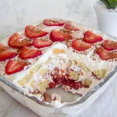 a cake with strawberries on top is sitting on a table next to a potted plant