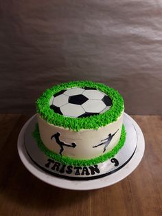 a soccer themed birthday cake with grass and soccer balls on the top, sitting on a wooden table