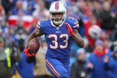 a football player running with the ball in his hand and people watching from the stands