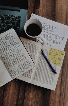 an open book with writing on it next to a cup of coffee and a laptop