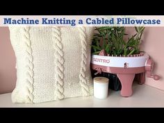 machine knitting a cabled pillow case on a table next to a potted plant