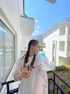 a man with dreadlocks holding a beer in his hand and looking out the window