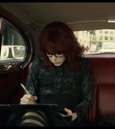 a woman sitting in the back seat of a car while writing on a clipboard