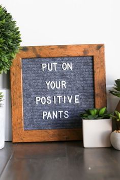 a sign that says put on your positive pants next to potted plants and succulents