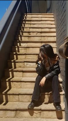 a woman sitting on the steps in front of a building