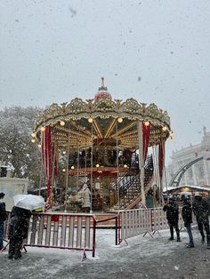 a merry go round in the snow with people standing around