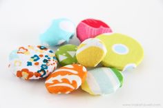 several different colored fabric balls on a white surface