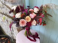 a bouquet of flowers sitting on top of a pink cake next to a brick wall