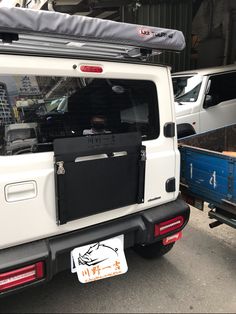 the back end of a white truck parked in front of a building with other vehicles