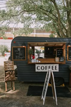 a coffee truck parked next to a tree and some signs on the side of it