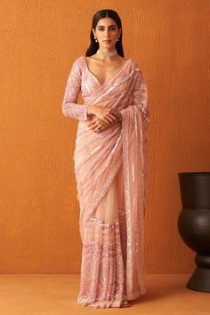 Rose pink net saree with pearl, tonal sequin and crystal embroidery in stripe pattern. Paired with full sleeve embroidered blouse and underskirt.
Components: 3
Pattern: Embroidery
Type Of Work: Pearl, sequin, crystal, stripe
Neckline: Leaf neck
Sleeve Type: Full sleeves
Fabric: Net
Color: Pink
Other Details: 
Back tassel tie-up
Sheer panelled saree
Occasion: Bride - Aza Fashions Full Sleeve Net Blouse, Full Sleeve Saree Blouse, Full Sleeve Saree, Full Sleeve Blouse Designs, Pearl Saree, Pink Net Saree, Sequin Saree Blouse, Net Saree Blouse, Saree Net