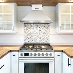 a stove top oven sitting inside of a kitchen next to white cabinets and counter tops